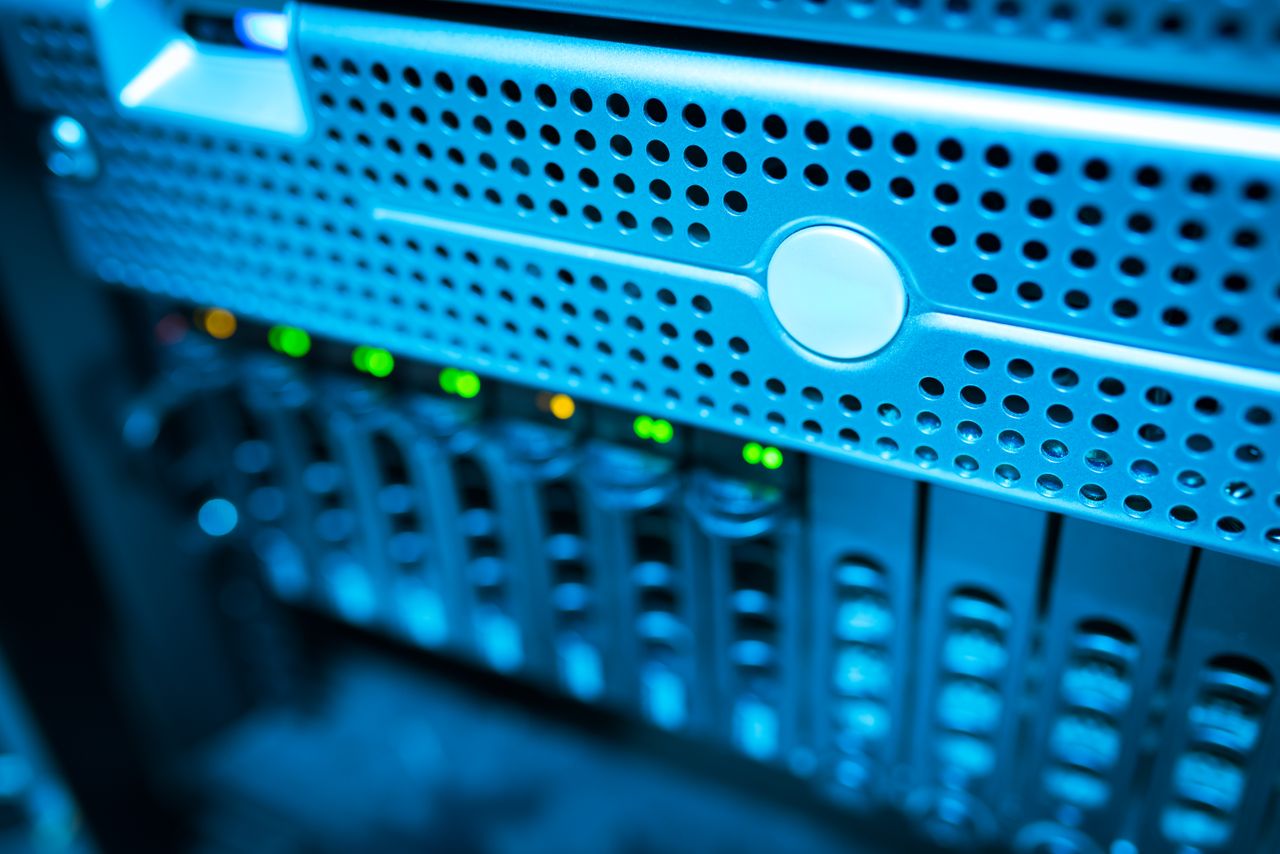 why-choose-us-02 Focused view of a modern data server rack with blinking lights in a blue-lit environment.