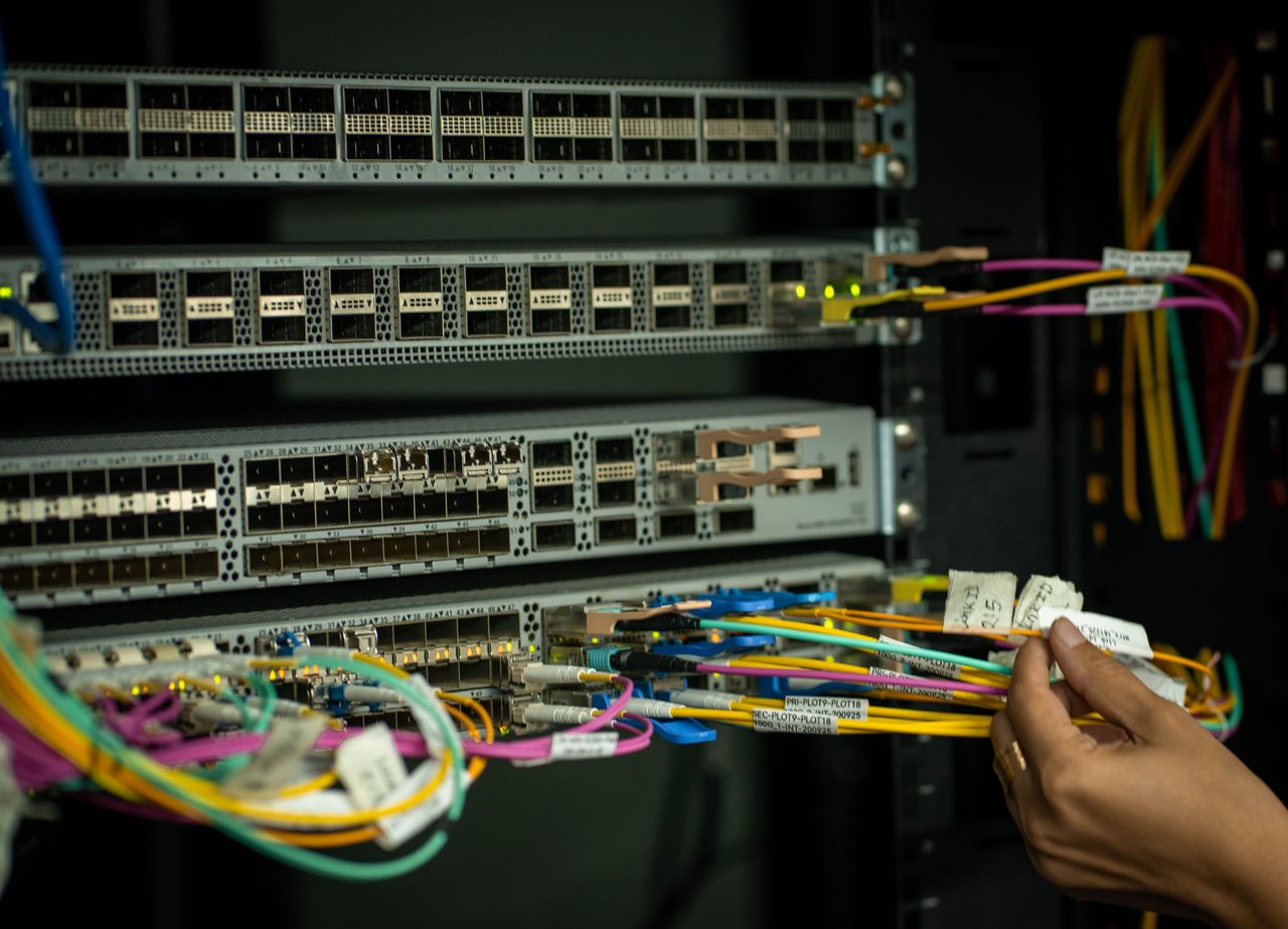 about-01 A hand managing fiber optic cables in a server room, showcasing modern connectivity.